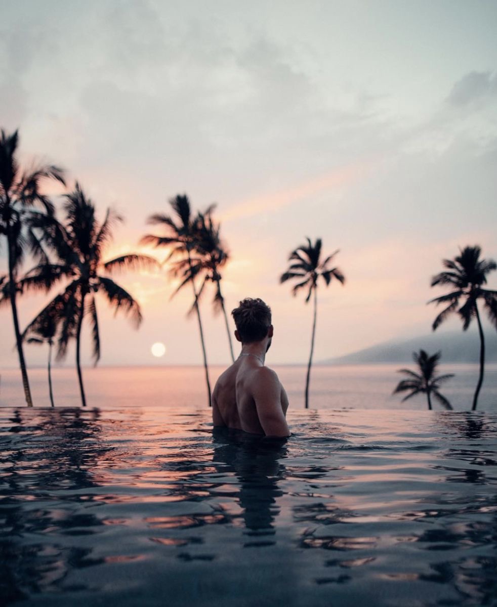 Silhouette of a person meditating at sunset with mountains and water